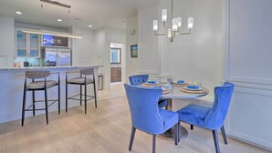 A modern kitchen with a central island, bar stools, and a dining table with chairs. - Lake LBJ Condo w/ Balcony & Shared Boat Docks (Horseshoe Bay)