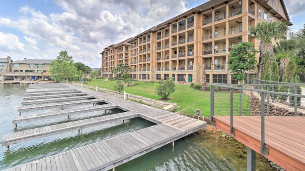 A hotel with multiple balconies, a dock extending into a body of water, and a well-maintained lawn area. - Lake LBJ Condo w/ Balcony & Shared Boat Docks (Horseshoe Bay)