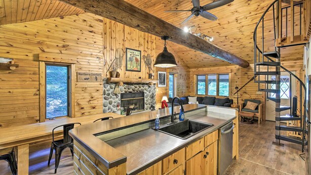 A wooden cabin interior with a kitchen, dining area, and a spiral staircase. - Waterfront Cottage w/ Dock on Papoose Lake! (Manitowish Waters)