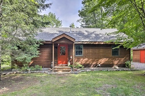 Une cabane en bois avec une porte rouge, un petit porche et un jardin bien entretenu.