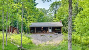 A cabin with a porch, surrounded by trees and a gravel driveway. - Waterfront Cottage w/ Dock on Papoose Lake! (Manitowish Waters)