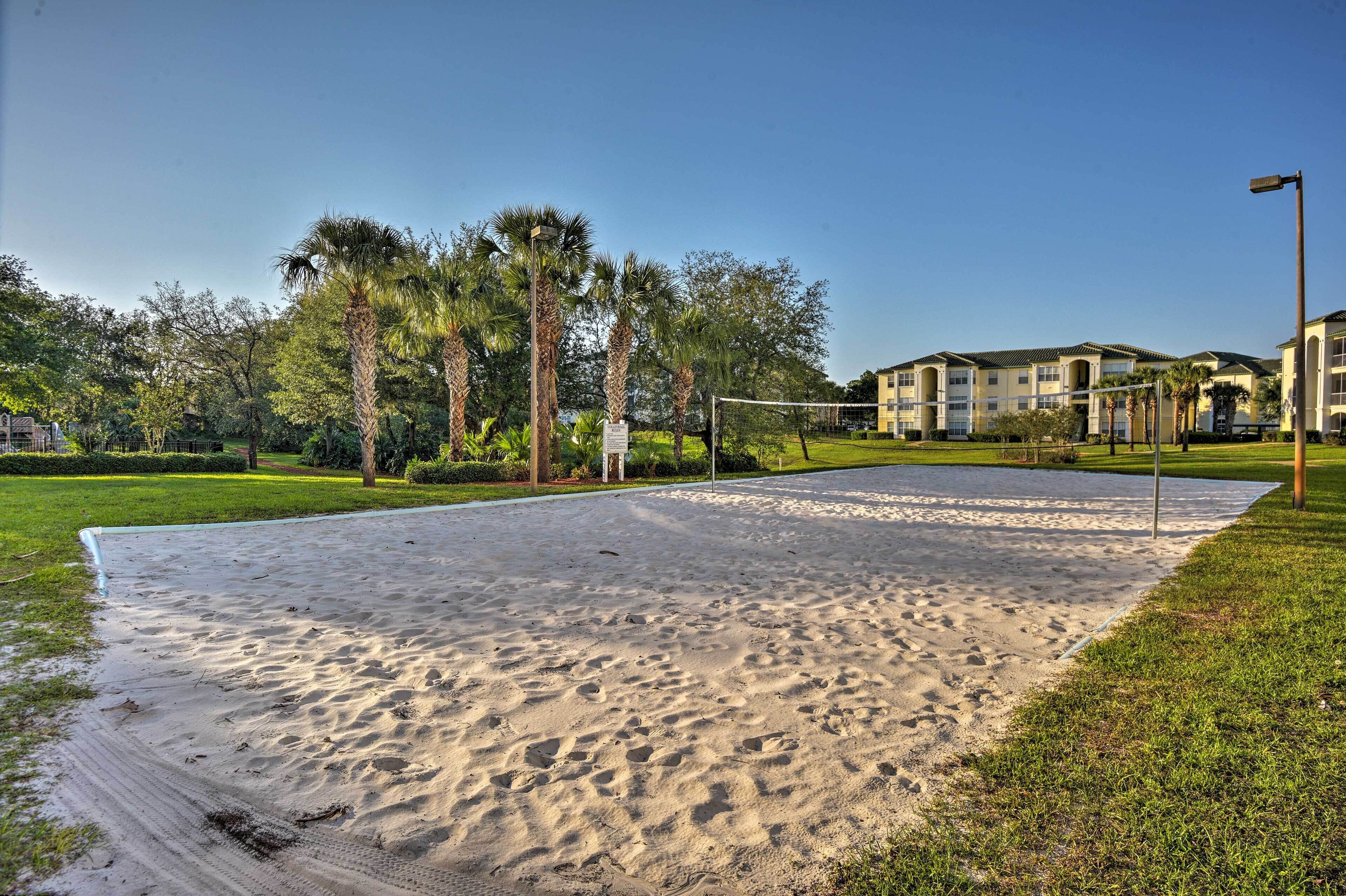 A sandy volleyball court with surrounding greenery and a building in the background.