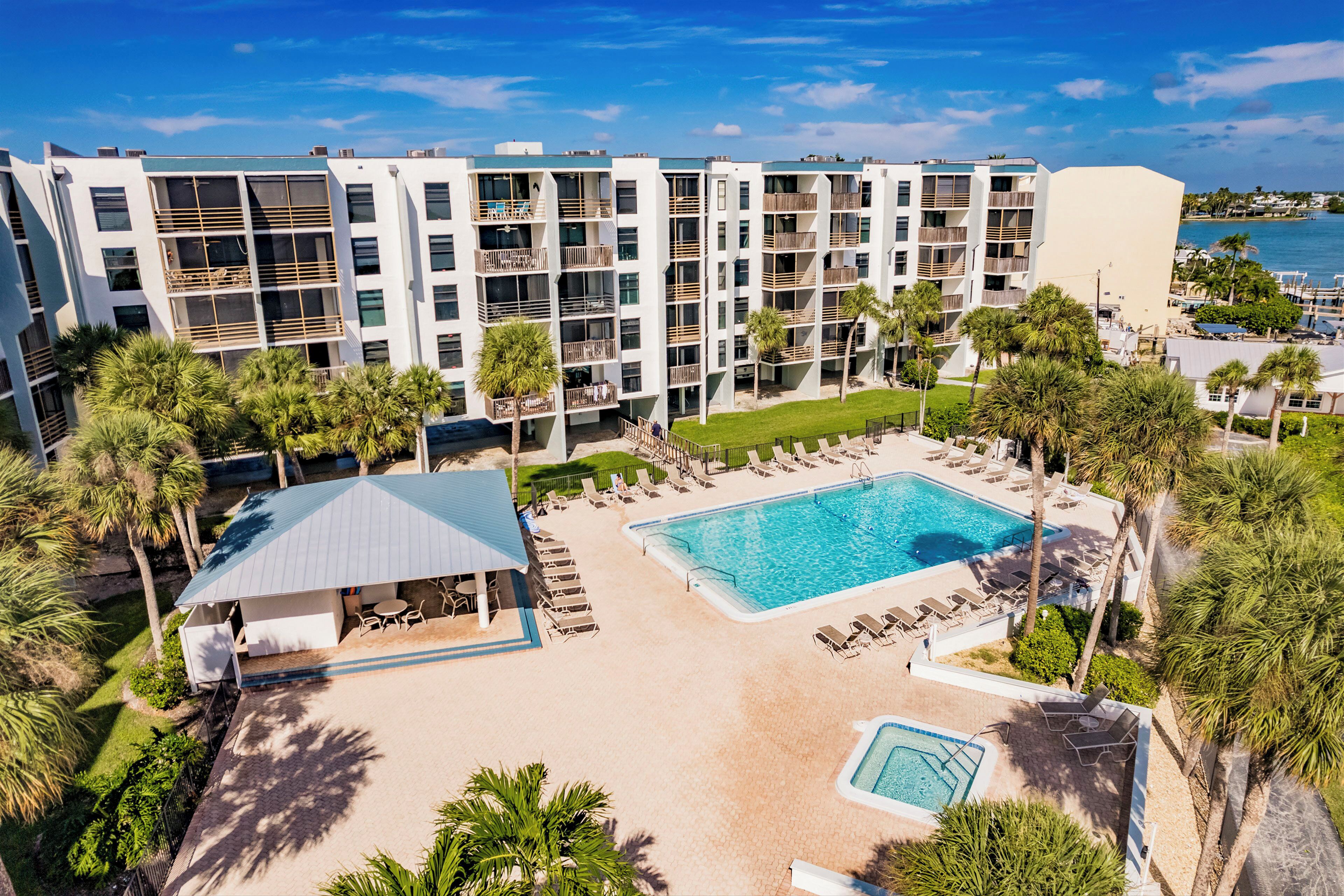 A hotel with a pool area, multiple balconies, and palm trees.