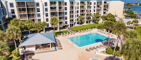 A hotel with a pool area, multiple balconies, and palm trees.