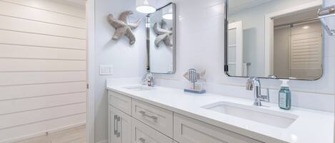 A modern bathroom with two sinks, a large mirror, and decorative starfish wall art.