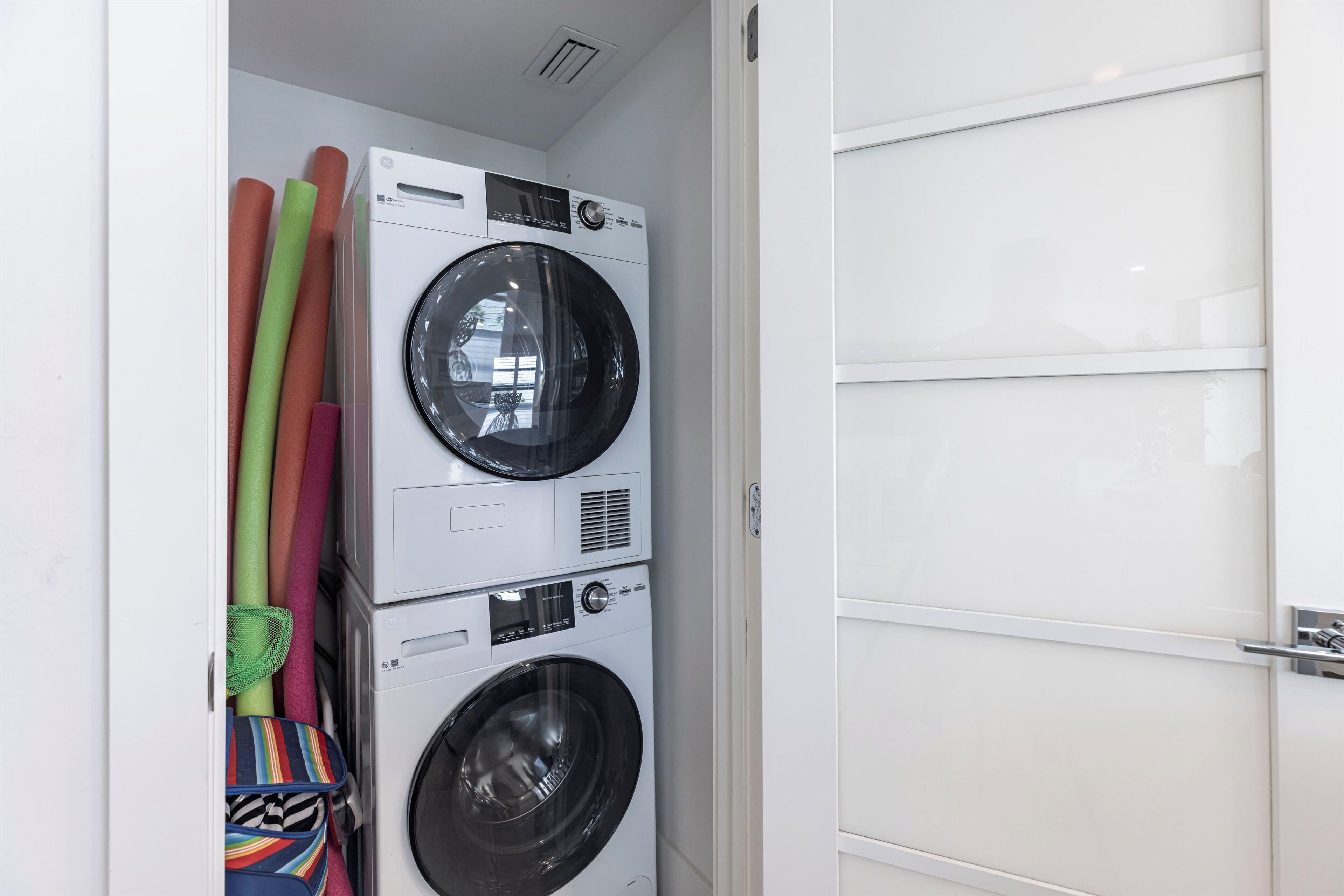 A laundry room with stacked washing machines and colorful towels.