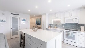 Een moderne keuken met witte kasten, een groot eiland en een ingebouwde oven.