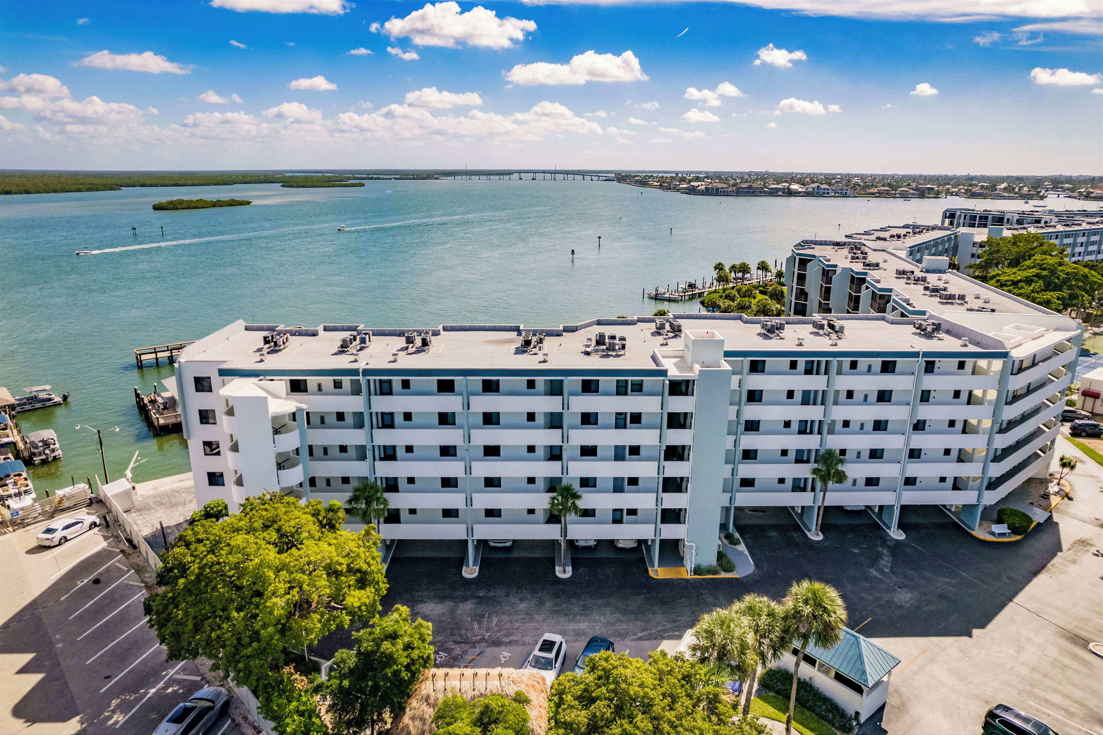 Een meerhoog hotel met een parkeerplaats en een jachthaven op de achtergrond.