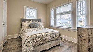 A bedroom with a bed, two windows, a ceiling fan, and a wooden cabinet. - Inviting Home, 1 Mi to High Point University! (High Point)