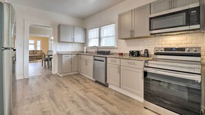 A modern kitchen with stainless steel appliances, light-colored cabinets, and a wooden floor. - Inviting Home, 1 Mi to High Point University! (High Point)