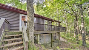 Une cabane dotée d’une terrasse en bois, d’un escalier et d’un garage.