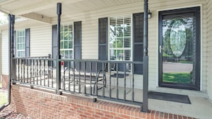 A house with a covered porch, a brick foundation, and a black door with a window. - Above-ground Pool & Backyard at Murfreesboro Home! (Murfreesboro)