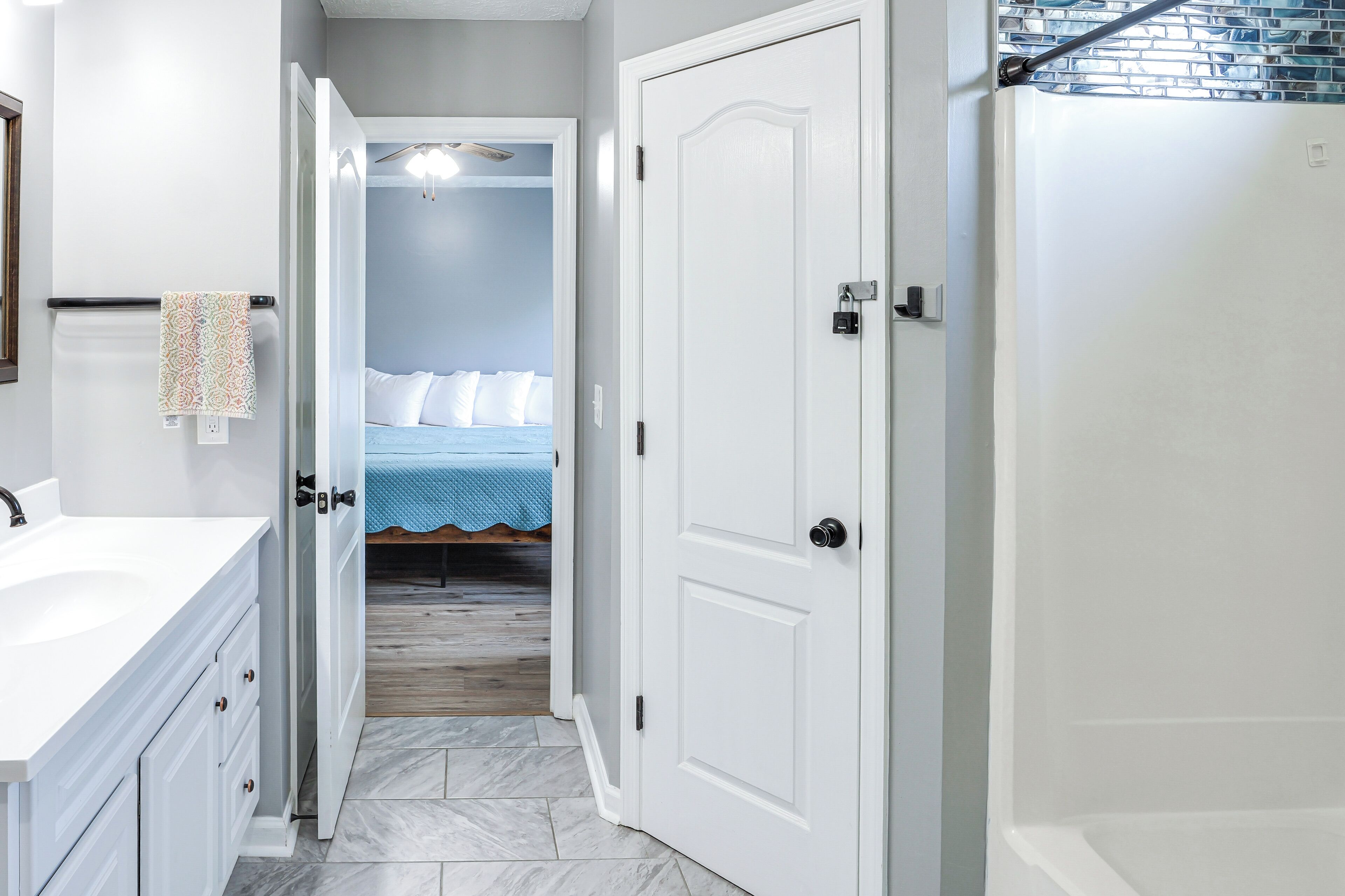 Une salle de bain avec un lavabo blanc, une serviette accrochée au mur et un espace douche.