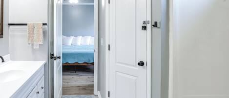 Une salle de bain avec un lavabo blanc, une serviette accrochée au mur et un espace douche.
