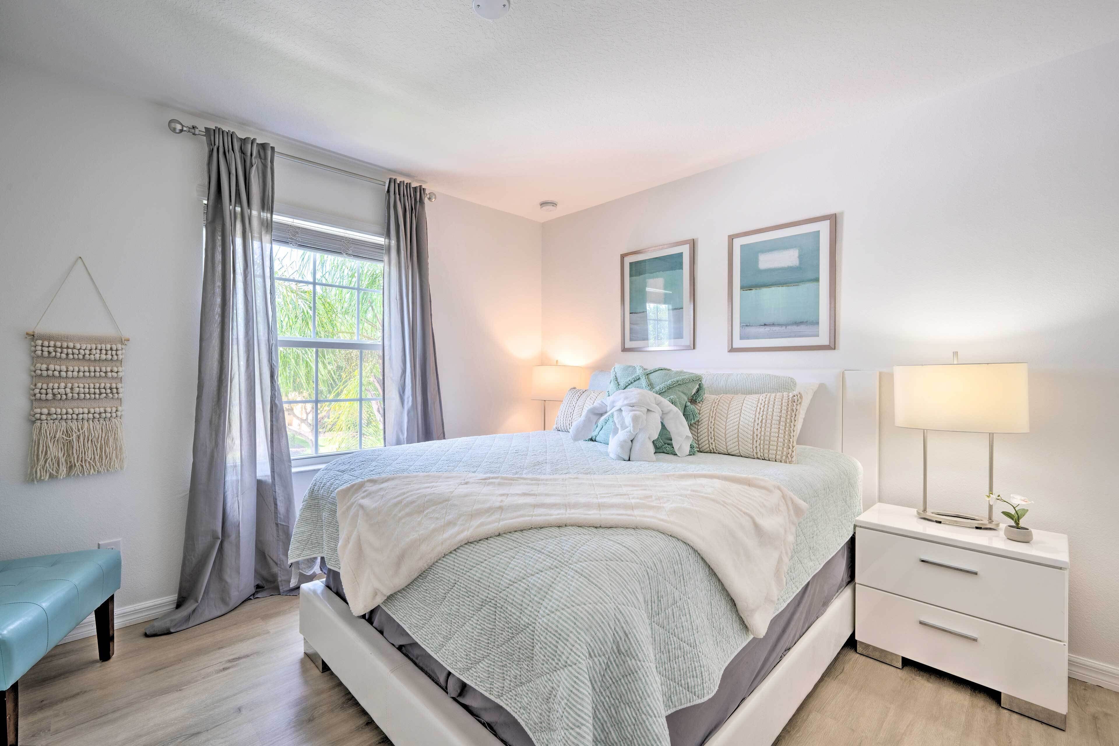 A bedroom with a bed, bedside tables, a bench, and a window with curtains.