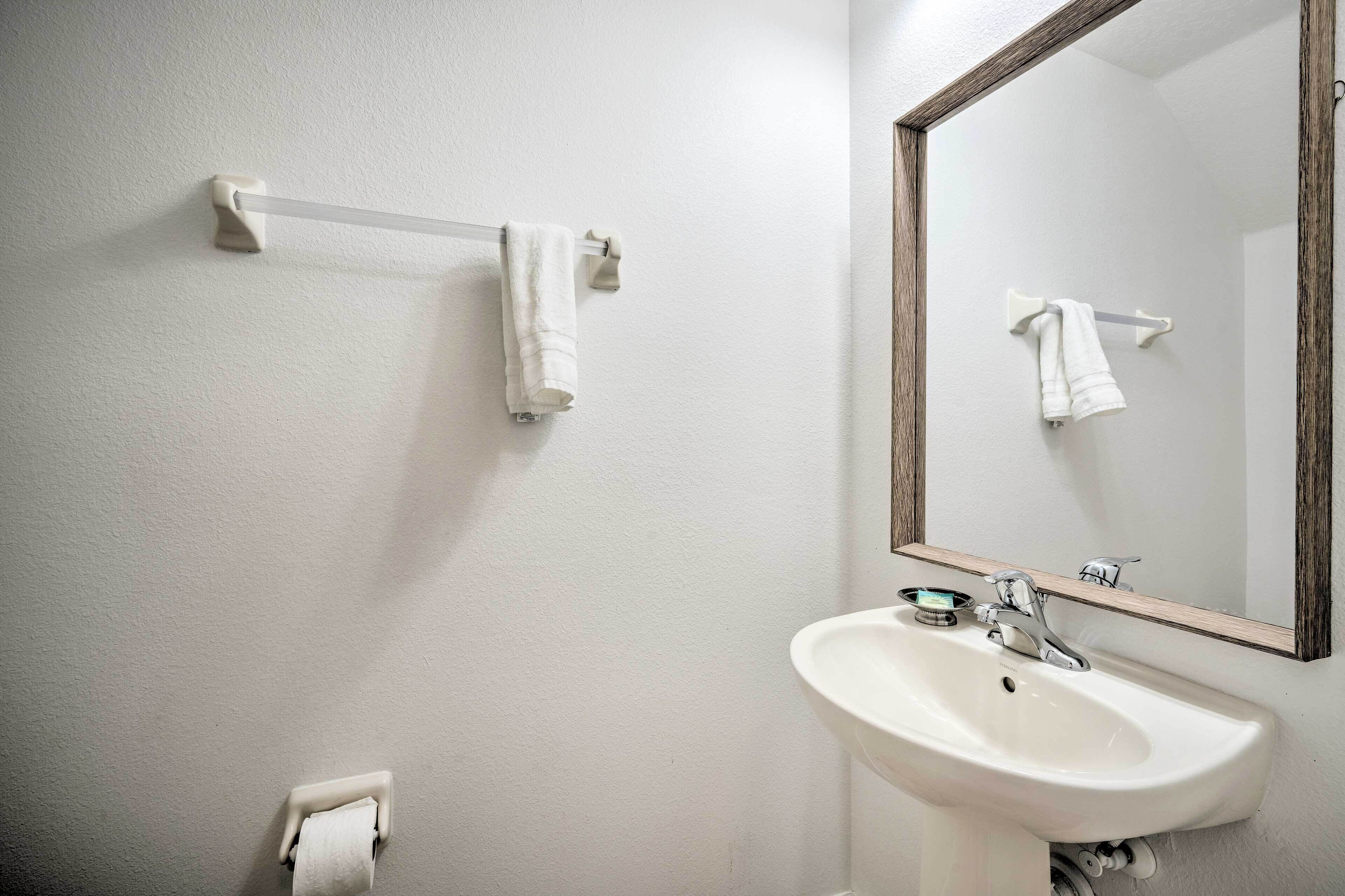 Un baño con un lavamanos blanco, un espejo y dos barras para toallas.