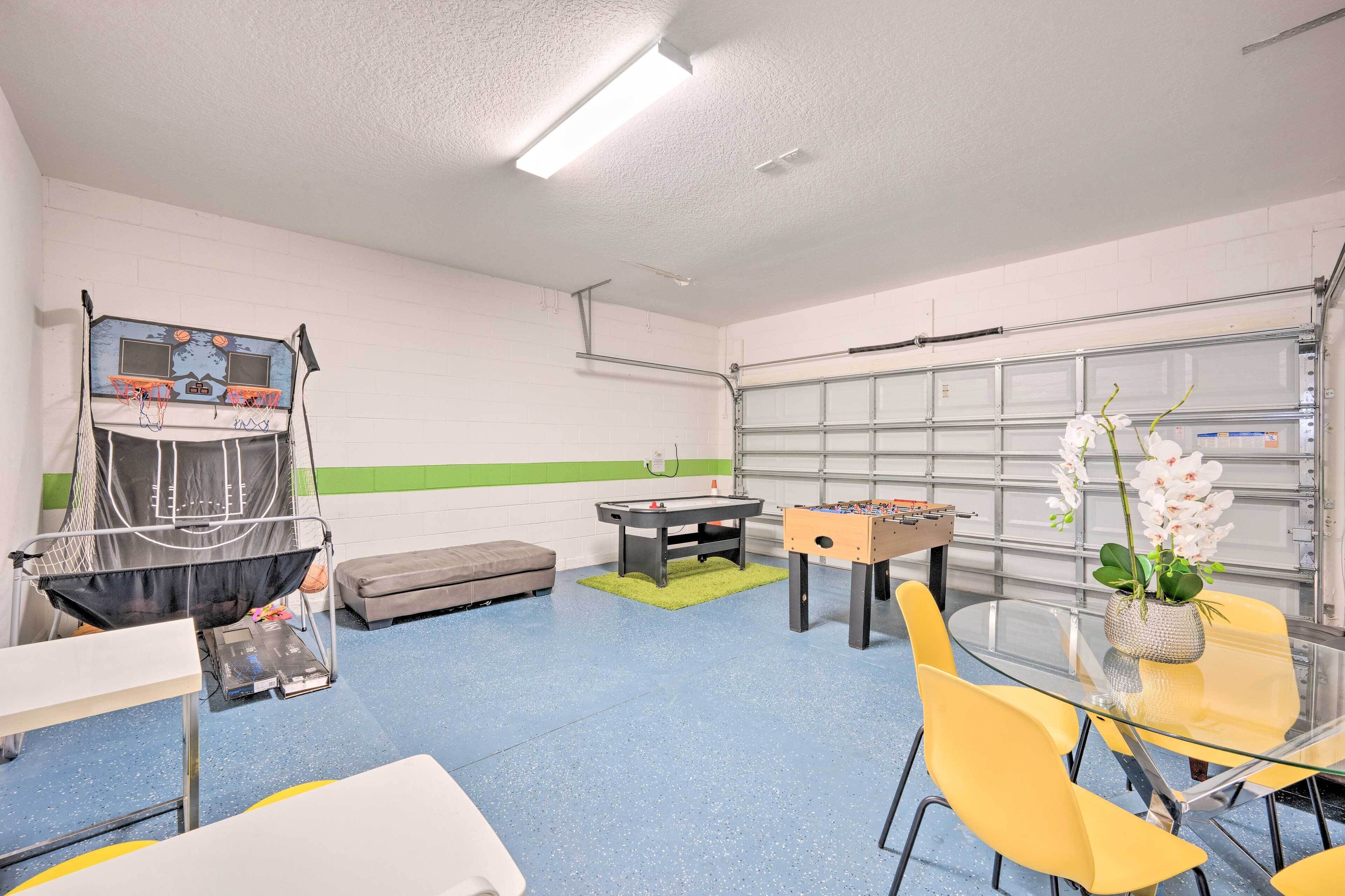 A recreational room with a foosball table, a pool table, and a basketball hoop.