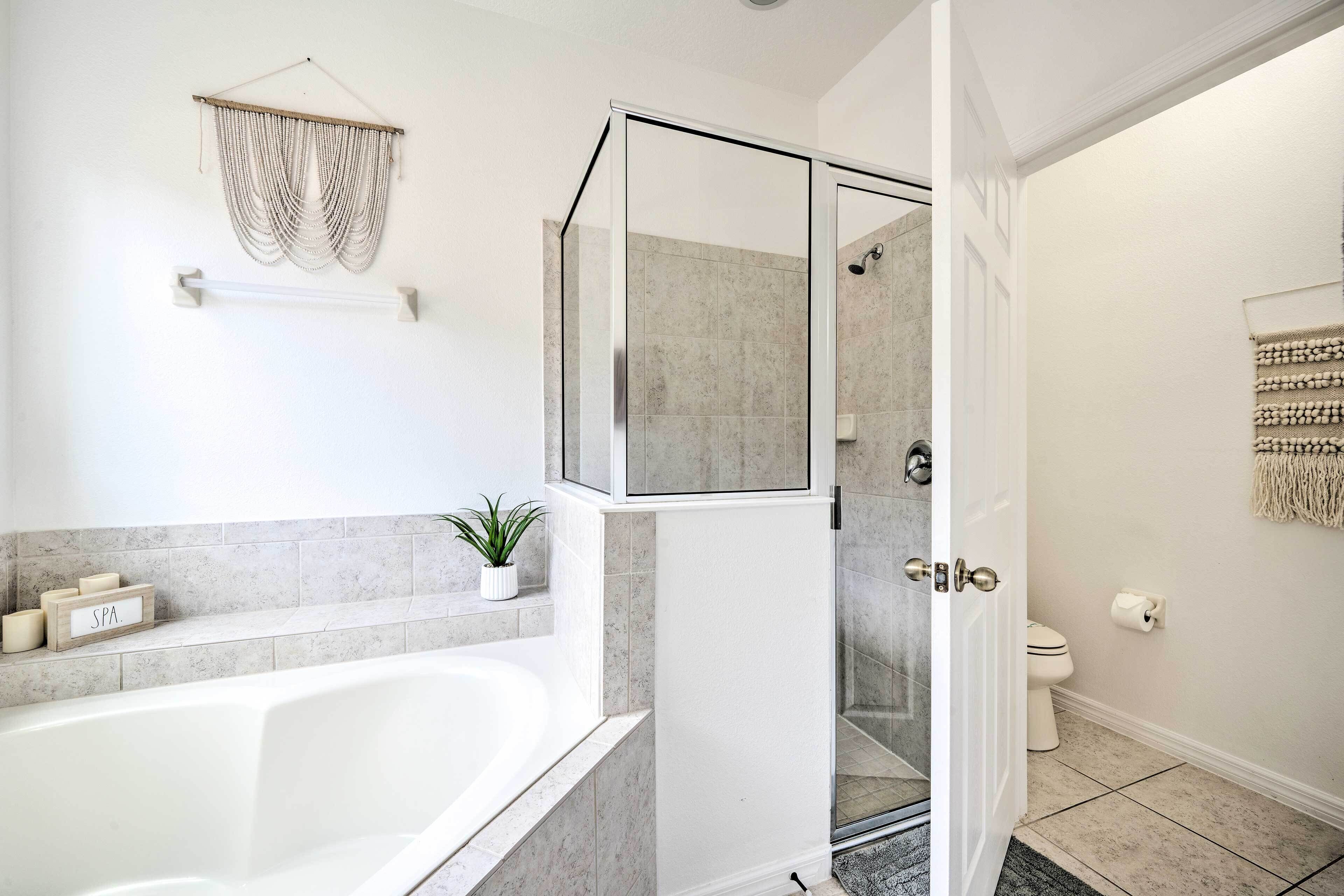 A modern bathroom with a bathtub, shower, and toilet.