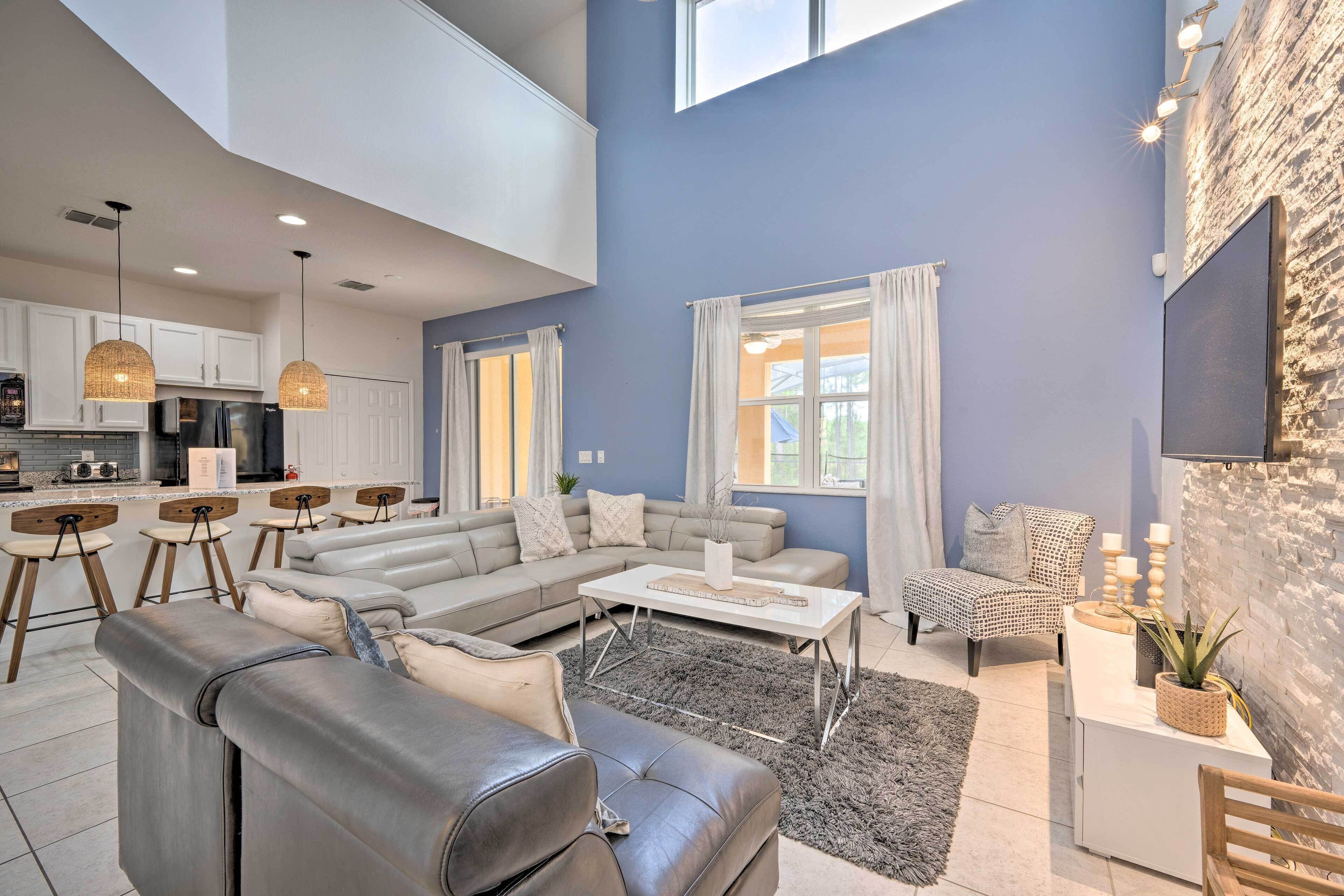 A spacious living area with a gray sofa, a coffee table, and a dining set.