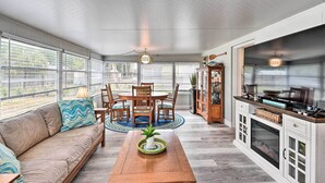 A sunlit room with a sofa, dining table, chairs, and a kitchen area with cabinets and a stove. - Pet-friendly Ormond Beach Home w/ Fire Pit! (Ormond Beach)