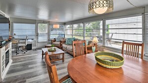 A spacious living room with a wooden dining table, comfortable seating, and large windows with blinds. - Pet-friendly Ormond Beach Home w/ Fire Pit! (Ormond Beach)