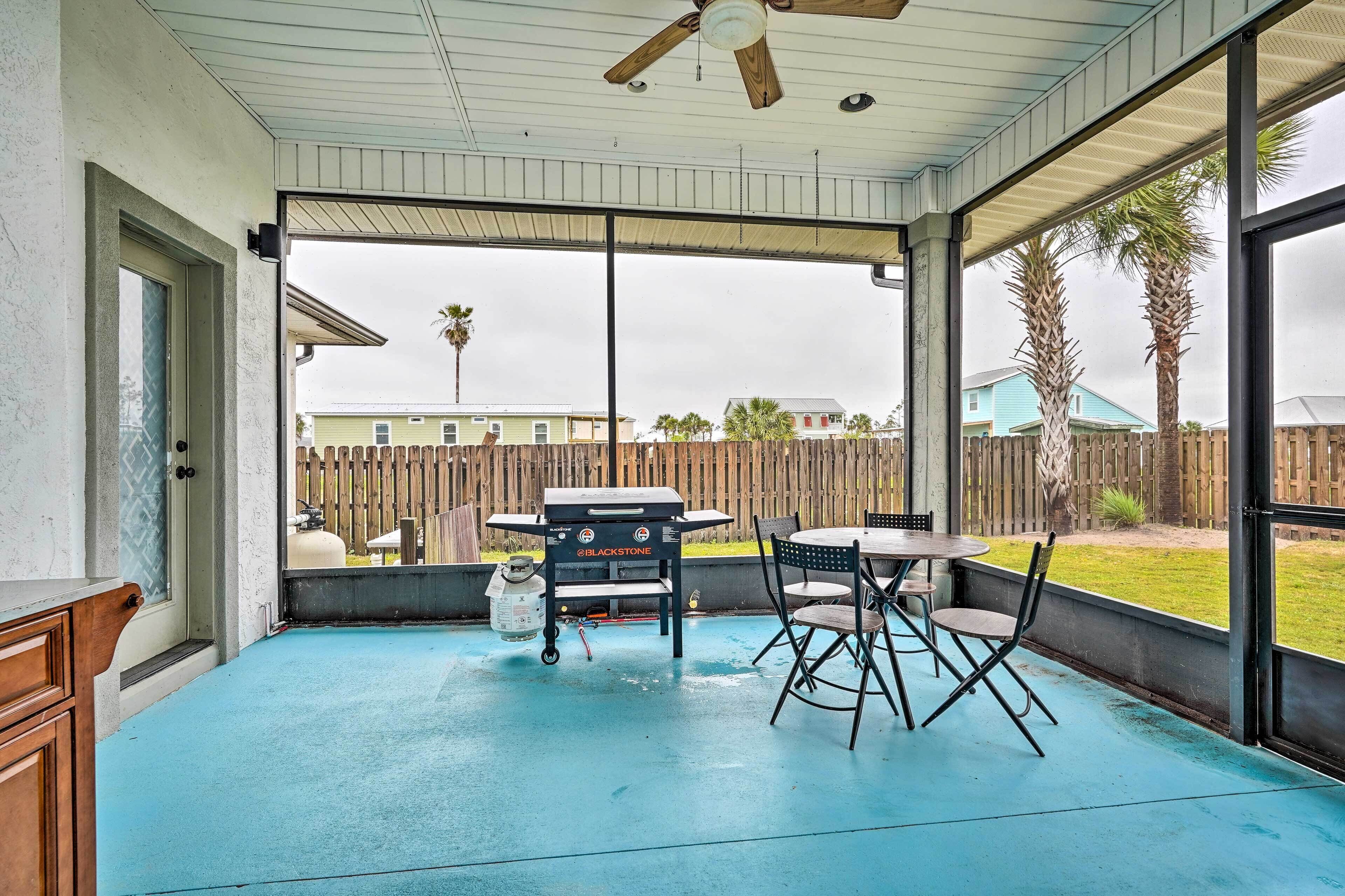 A covered patio with a pool table, a grill, and a ceiling fan.