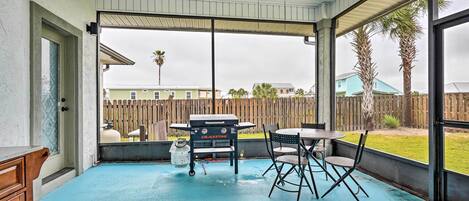 A covered patio with a pool table, a grill, and a ceiling fan.