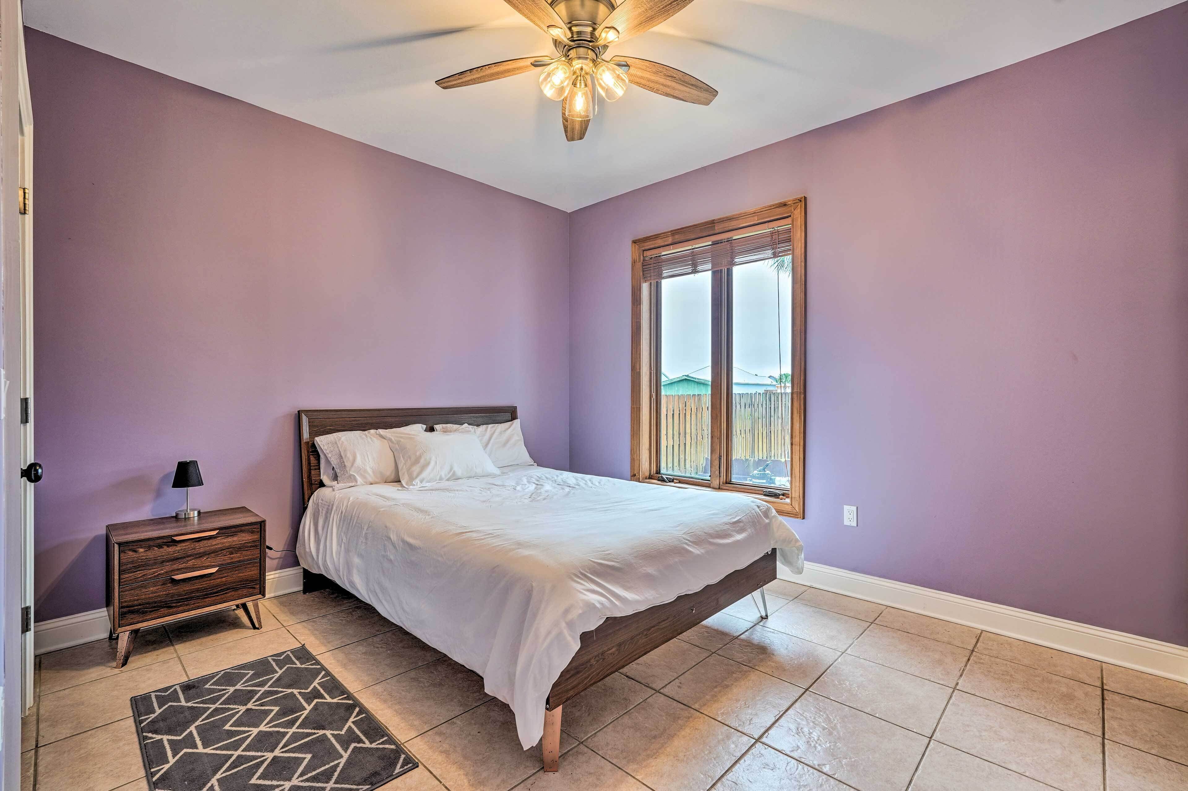 A bedroom with a bed, nightstand, and a window with a view.