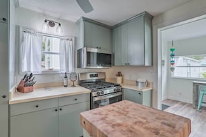 A kitchen with a gas stove, oven, microwave, and a wooden table.