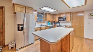 A kitchen with wooden cabinets, a stainless steel refrigerator, a microwave, and a large island. - Pet-friendly Caldwell Home Rental Near Lake! (Caldwell)