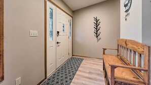 A hallway with a wooden bench, a patterned rug, and a wall-mounted decoration. - Pet-friendly Caldwell Home Rental Near Lake! (Caldwell)