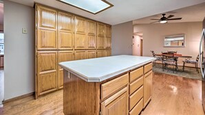 A kitchen with wooden cabinets, a white countertop, a ceiling fan, and a dining area with a table and chairs. - Pet-friendly Caldwell Home Rental Near Lake! (Caldwell)