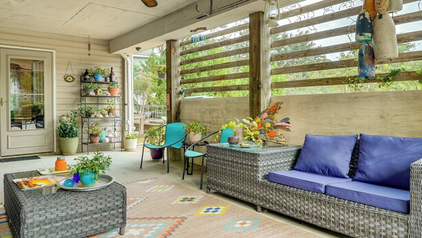 Une terrasse couverte, aménagée avec des meubles en osier, un canapé et une table basse.