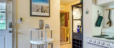 A kitchen with a stove, a bar stool, and a framed picture on the wall.