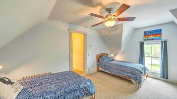 A bedroom with two single beds, a ceiling fan, and a window with curtains.