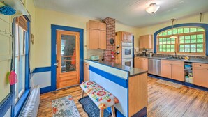 A kitchen with wooden cabinets, a built-in stove, and a large window. - Rustic & Historic Guildhall Farmhouse w/ Fire Pit! (Guildhall)
