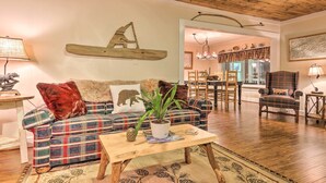 A cozy living room with a plaid sofa, a wooden coffee table, and a dining area in the background. - Mtn Views + Fire Pit: Serene Chimney Rock Abode (Chimney Rock)