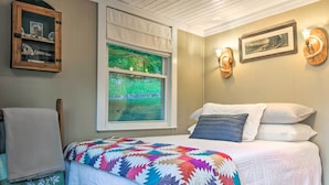 A bedroom with a bed, a window with a view, a quilt, and wall-mounted decor. - Mtn Views + Fire Pit: Serene Chimney Rock Abode (Chimney Rock)