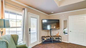 A living room with a television, a sofa, a coffee table, and a door. - Granbury Studio - 10 Mins From Town + The Lake! (Granbury)