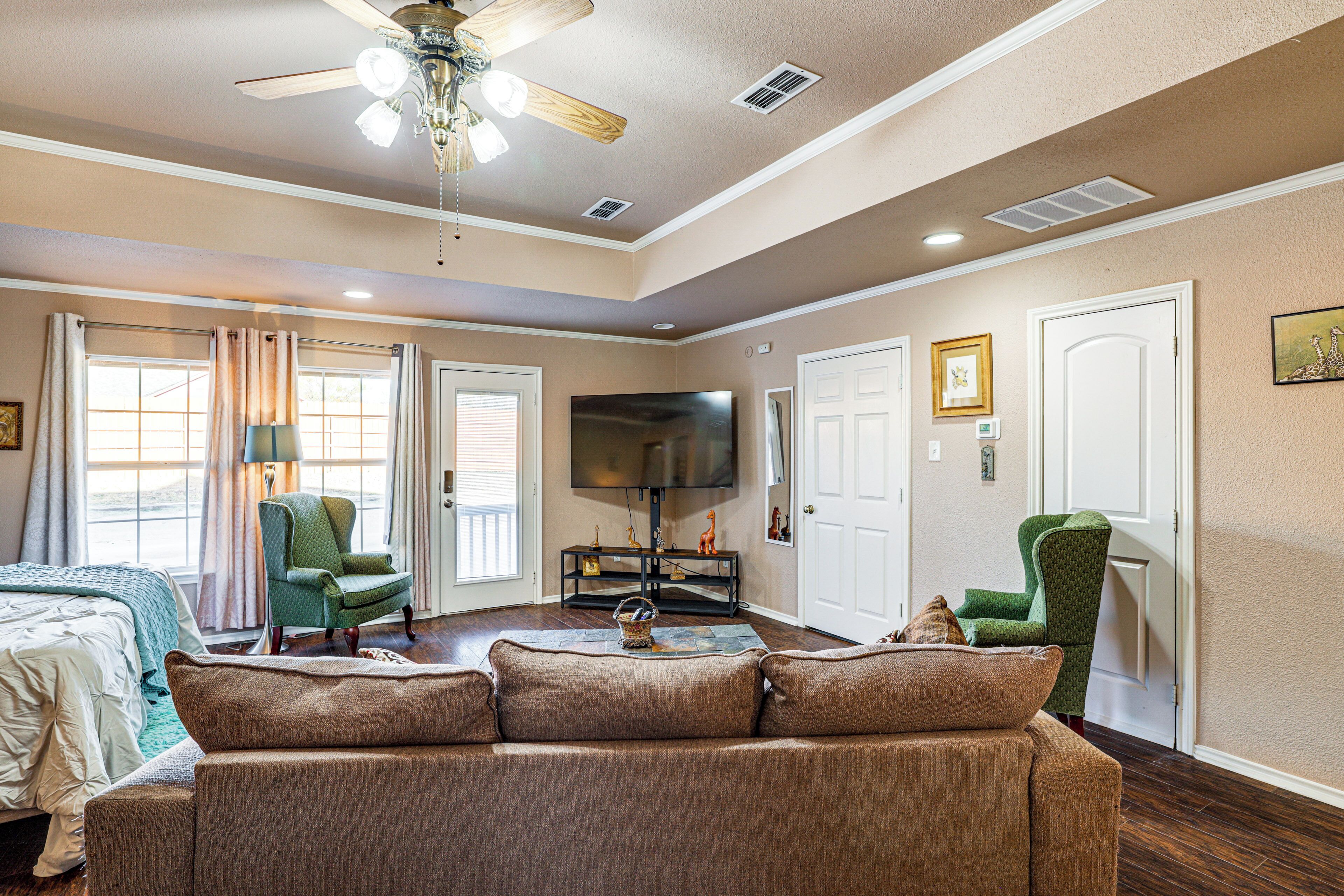 A living room with a sofa, chairs, a TV, and a ceiling fan.