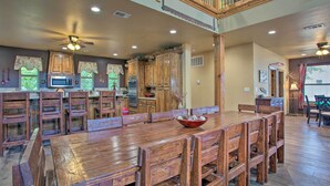A spacious kitchen with wooden cabinets, a large dining table, and a ceiling fan. - Kingston Home w/ Pickleball: Steps to Lake Texoma! (Kingston)
