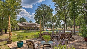 An outdoor patio area with stone flooring, wooden furniture, and potted plants. - Kingston Home w/ Pickleball: Steps to Lake Texoma! (Kingston)