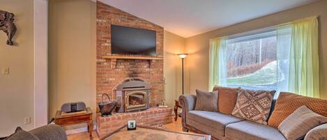 A living room with a brick fireplace, a flat-screen TV, a sofa, and a coffee table.