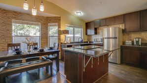 A modern kitchen with a central island, dark wooden cabinets, and a stone accent wall. - Family-friendly San Antonio Abode w/ Patio! (San Antonio)