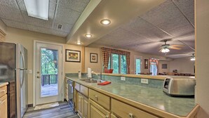 A kitchen with wooden cabinets, a stainless steel refrigerator, a granite countertop, and a ceiling fan.