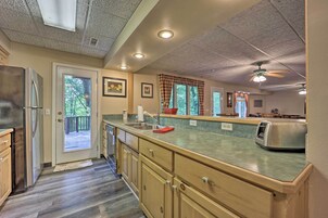 A kitchen with wooden cabinets, a stainless steel refrigerator, a granite countertop, and a ceiling fan.