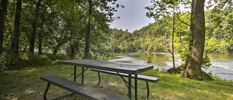 A picnic table in a forested area with a river in the background.
