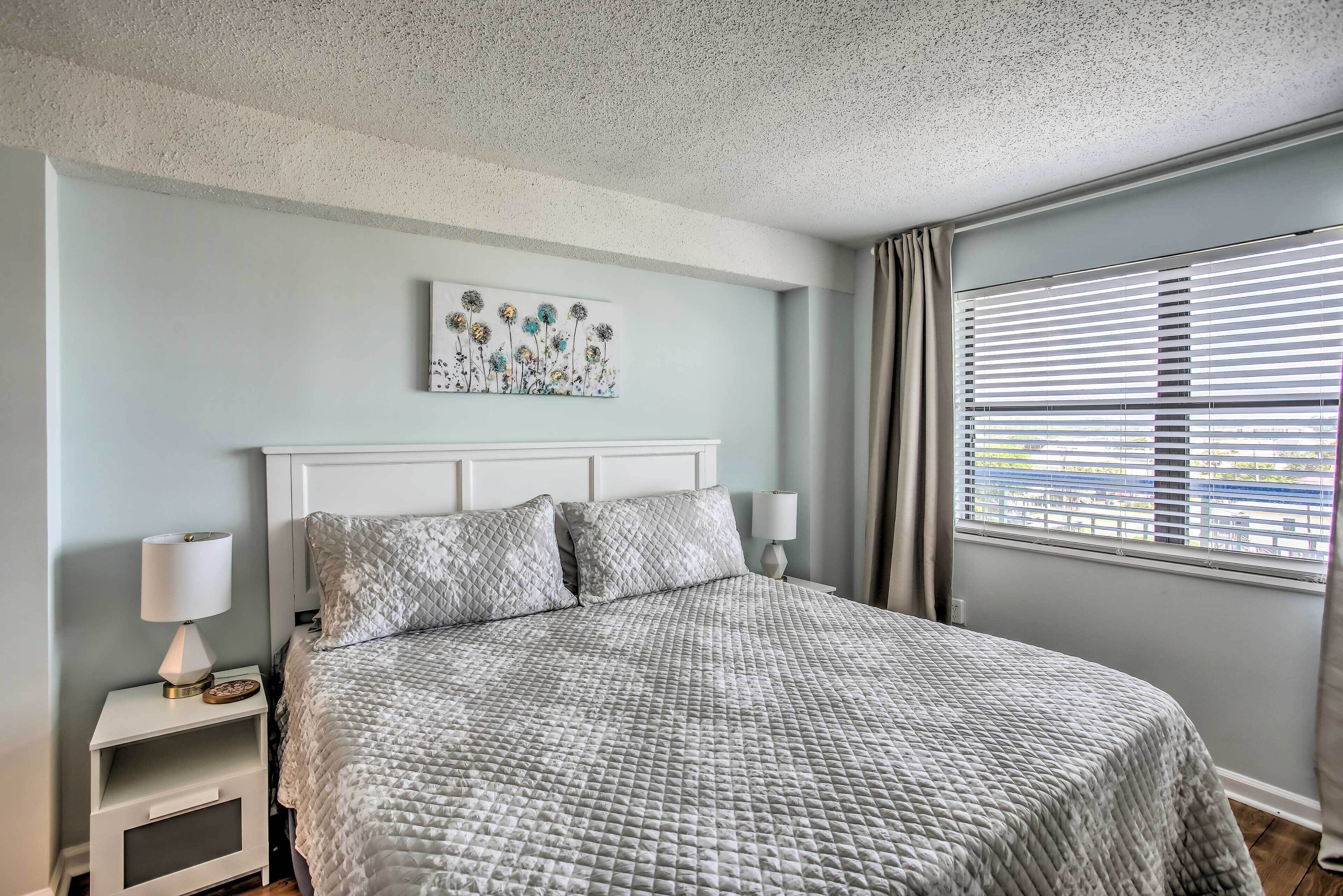 A bedroom with a bed, nightstands, a wall art piece, and a window with blinds.