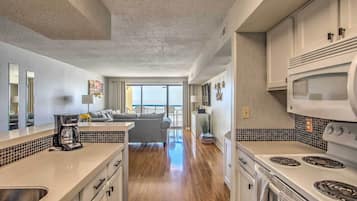 A modern kitchen with a large island, white cabinets, and a view to the living area.