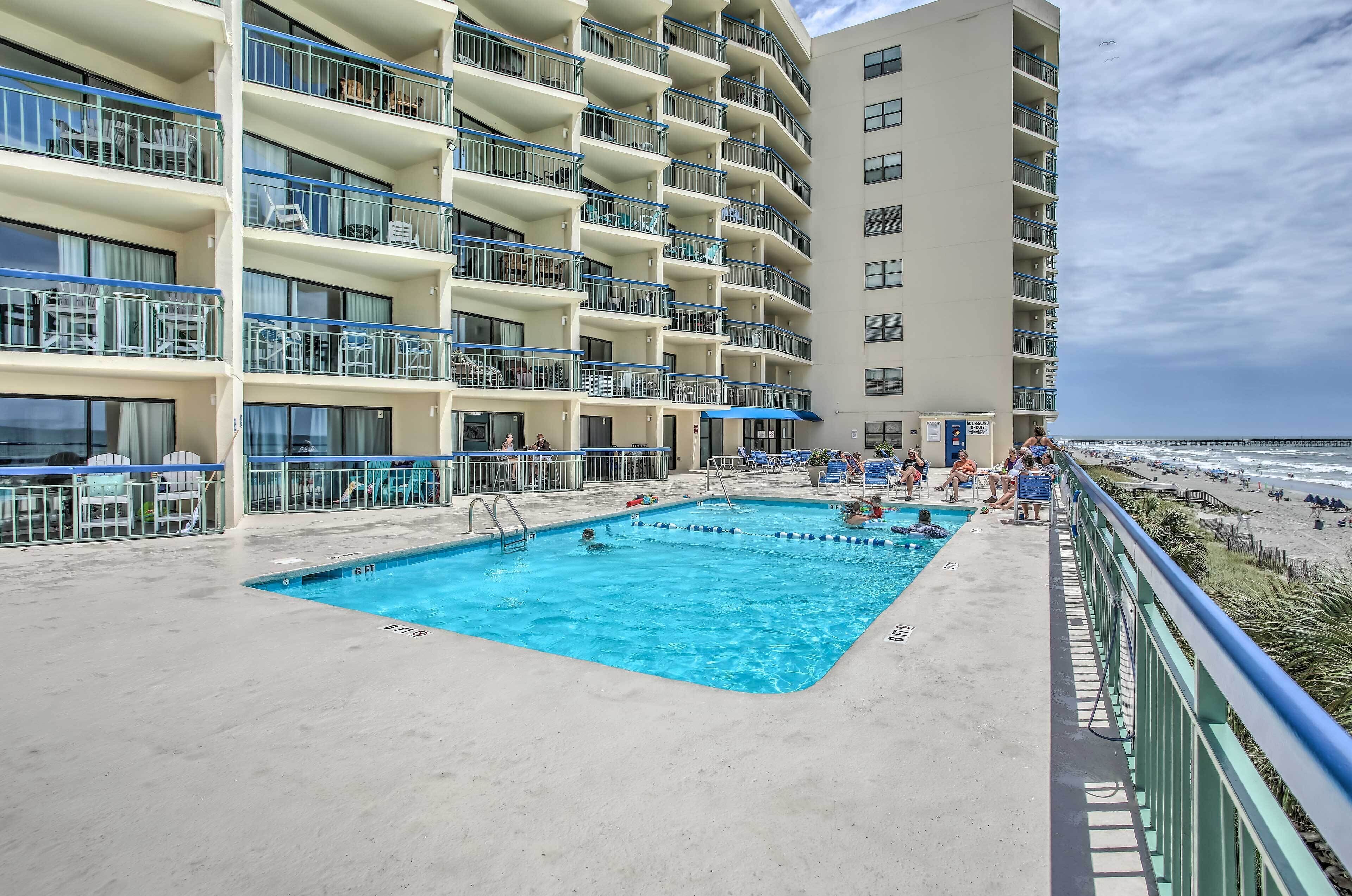 A hotel with a swimming pool, balconies, and a beach view.